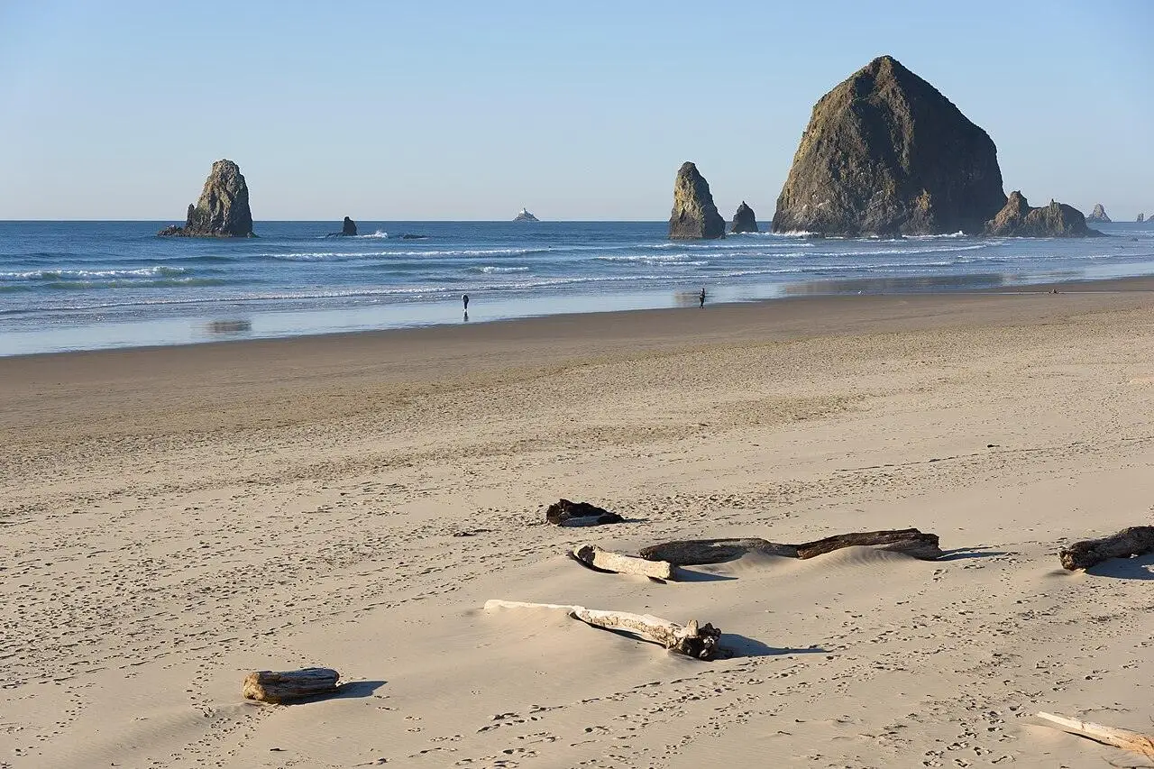 Haystack Rock and the beach at Cannon Beach under a bright sky.